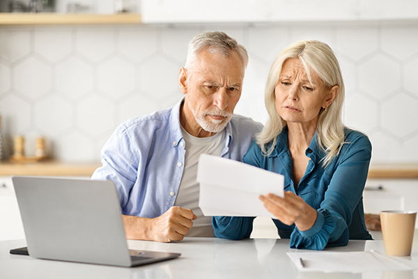 upset-elderly-spouses-checking-financial-documents-while-calculating-family-budget-home Couple reviewing letter concerned about SSDI Overpayments
